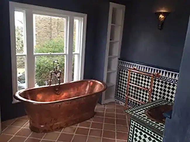 a bathroom with a copper bathtub and tiled floors