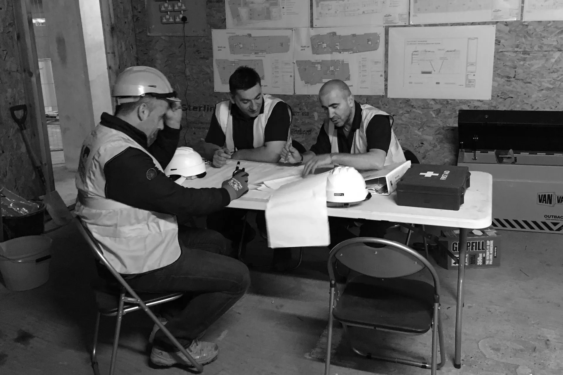 a group of men sitting around a table working on a project